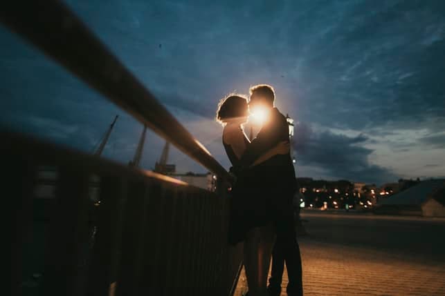 two figures kissing in the evening outdoors