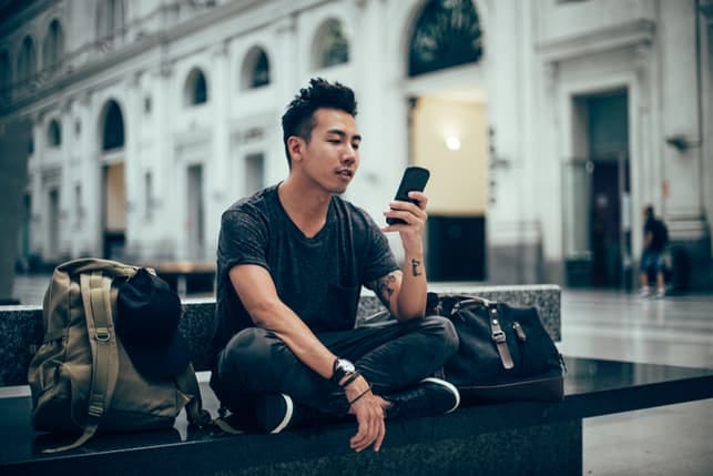 a young asian guy checking his phone outdoors