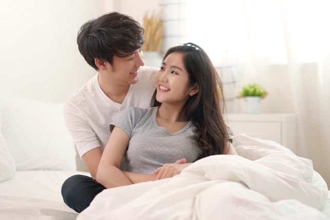 a beautiful asian couple is hugging at home