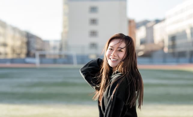 a young asian woman is smiling outdoors